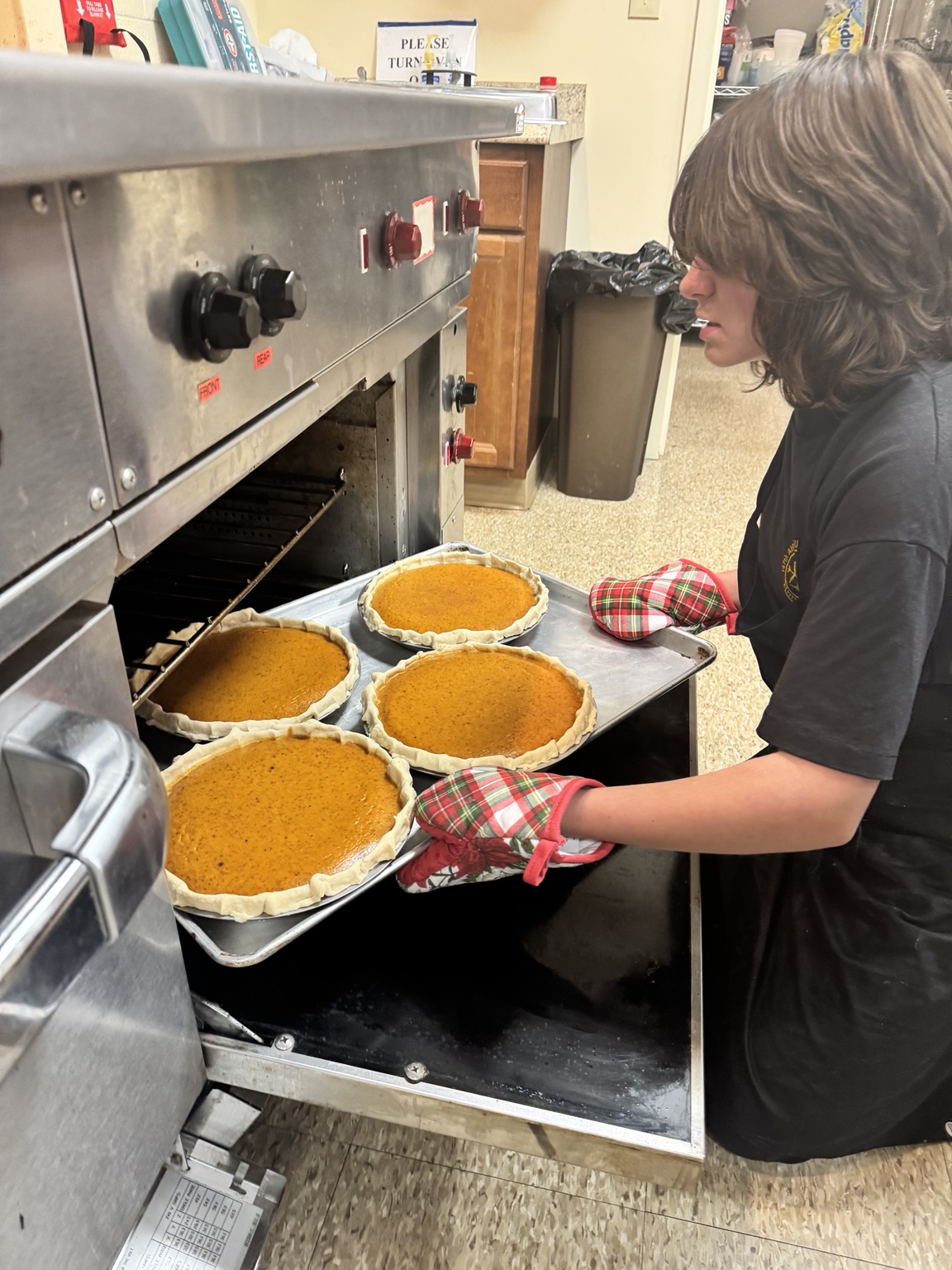 Volunteer pulling pumpkin pies from the oven
